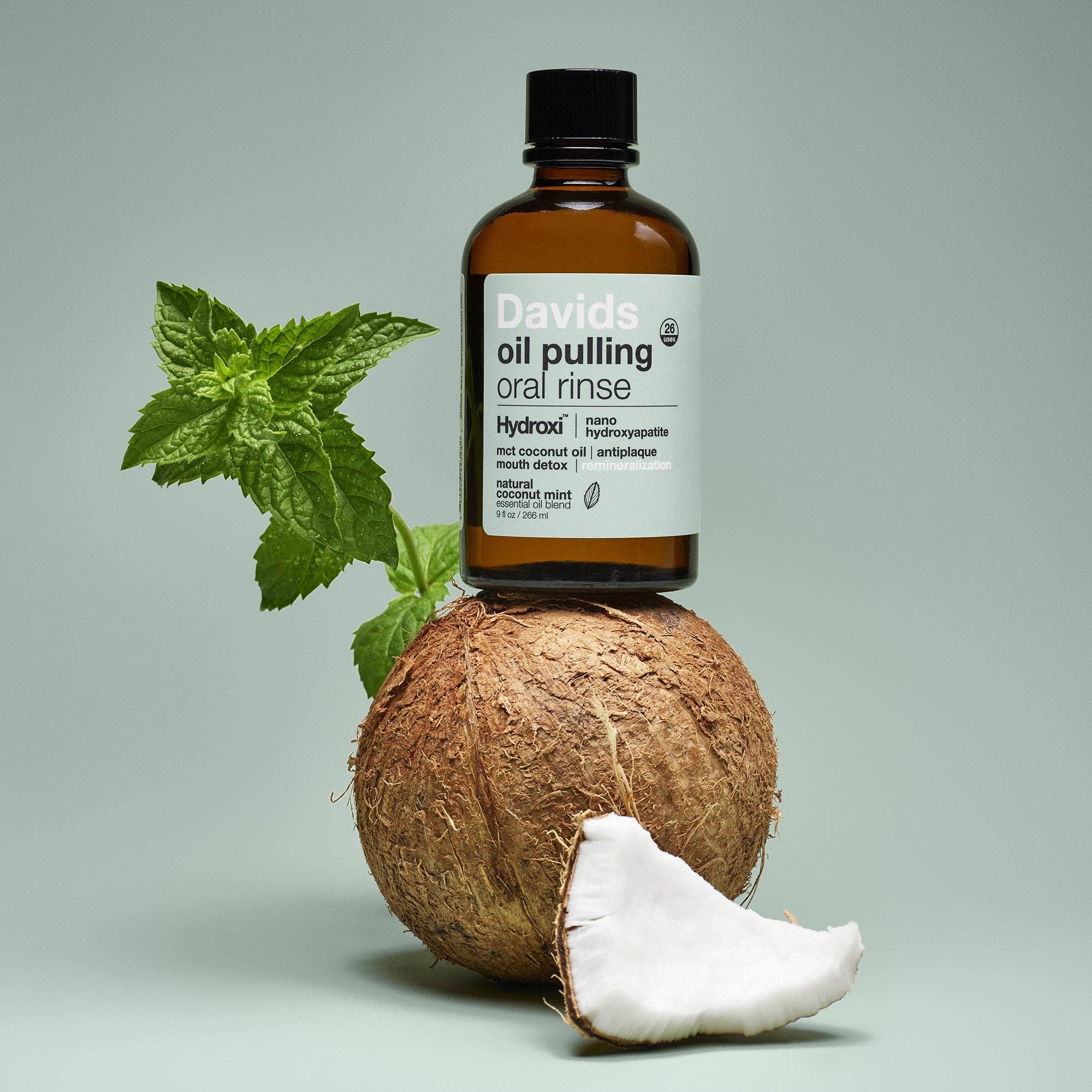 Bottle of Davids oil pulling oral rinse on a coconut with a green leaf on a gray background