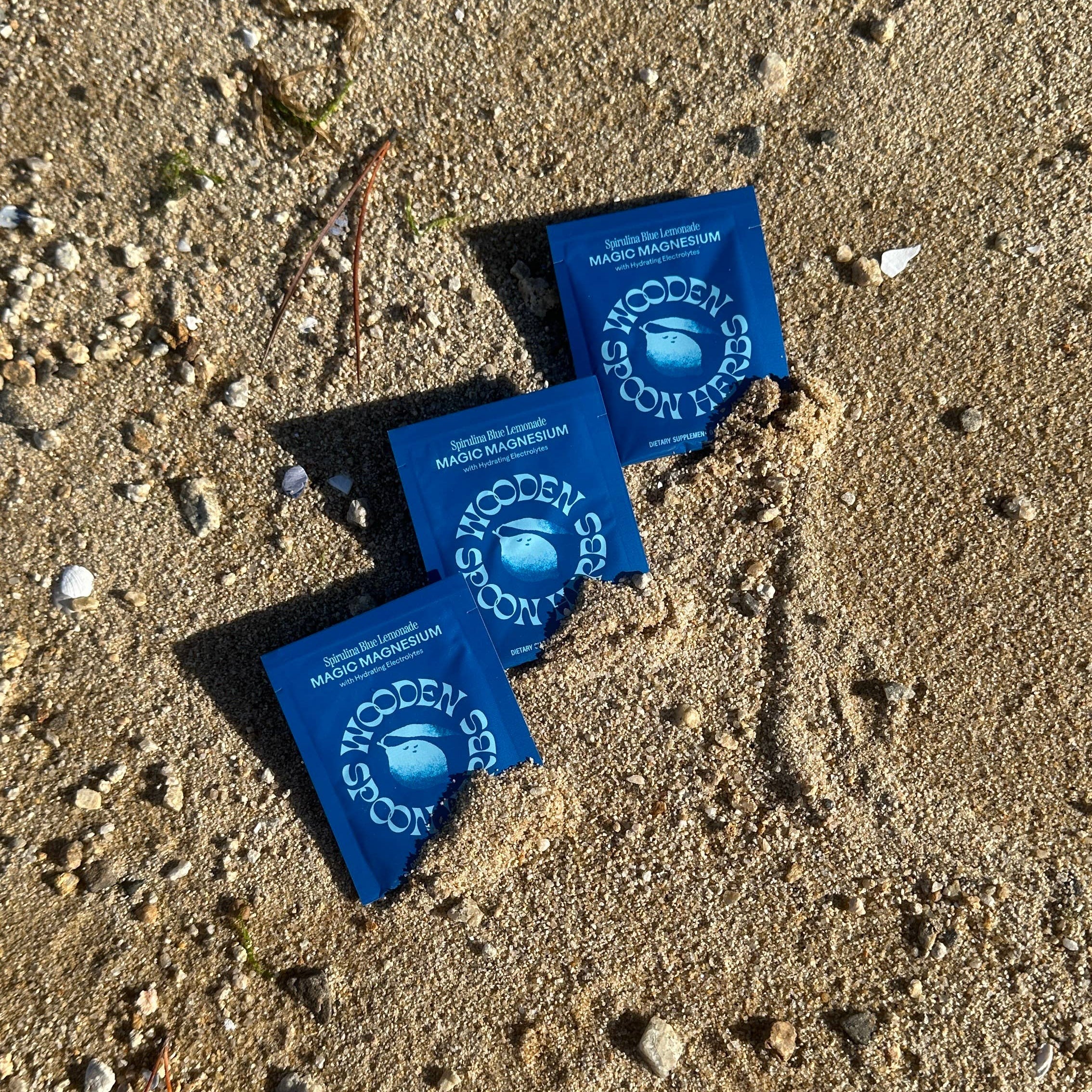 Three blue packets on a sandy surface