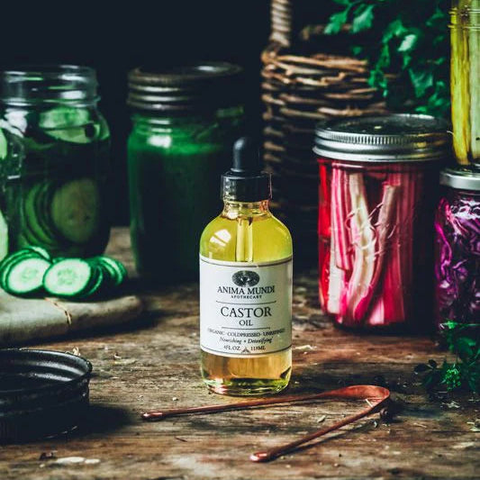 Bottle of Castor oil on a wooden surface with jars and vegetables in the background