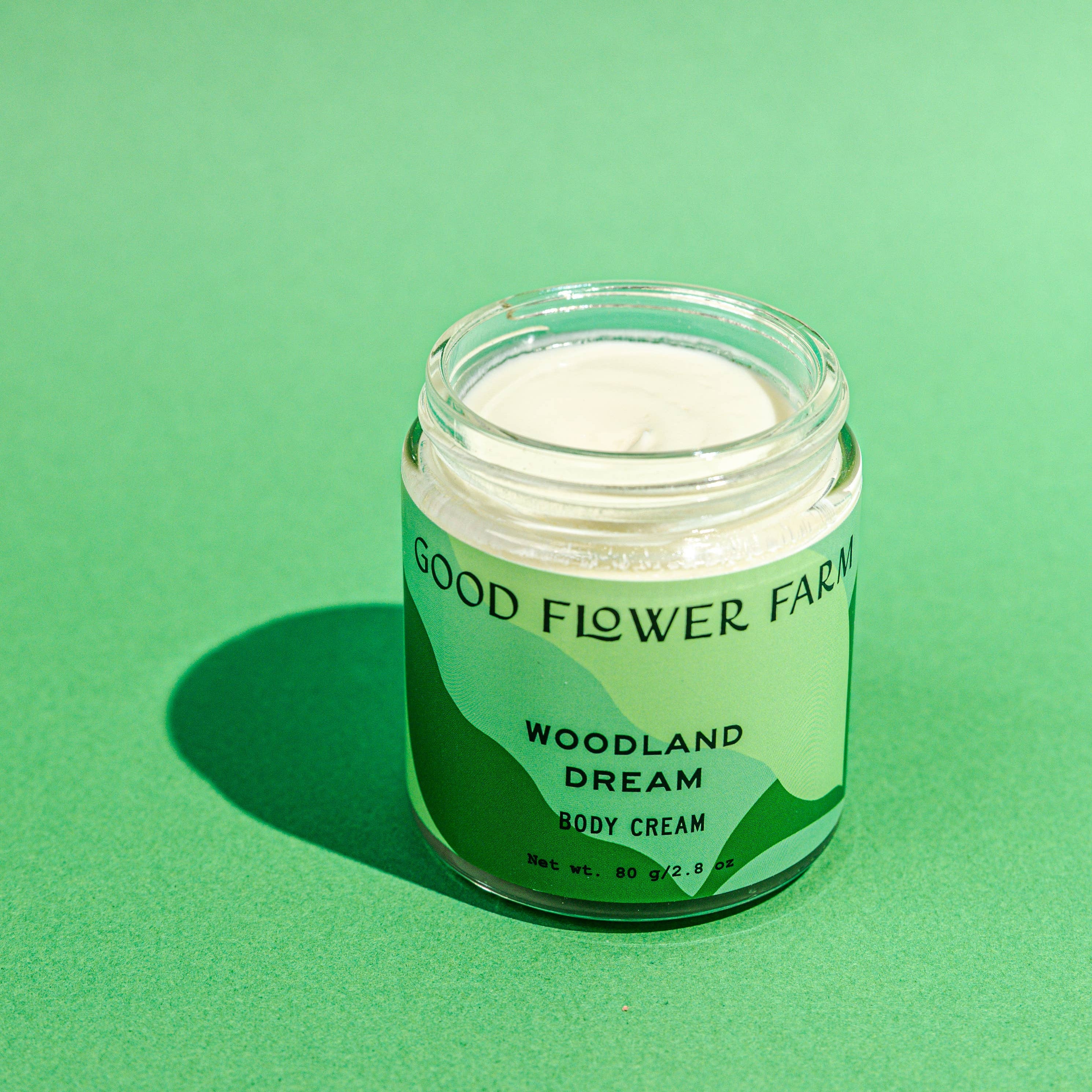 Jar of Good Flower Farm Woodland Dream body cream on a green background