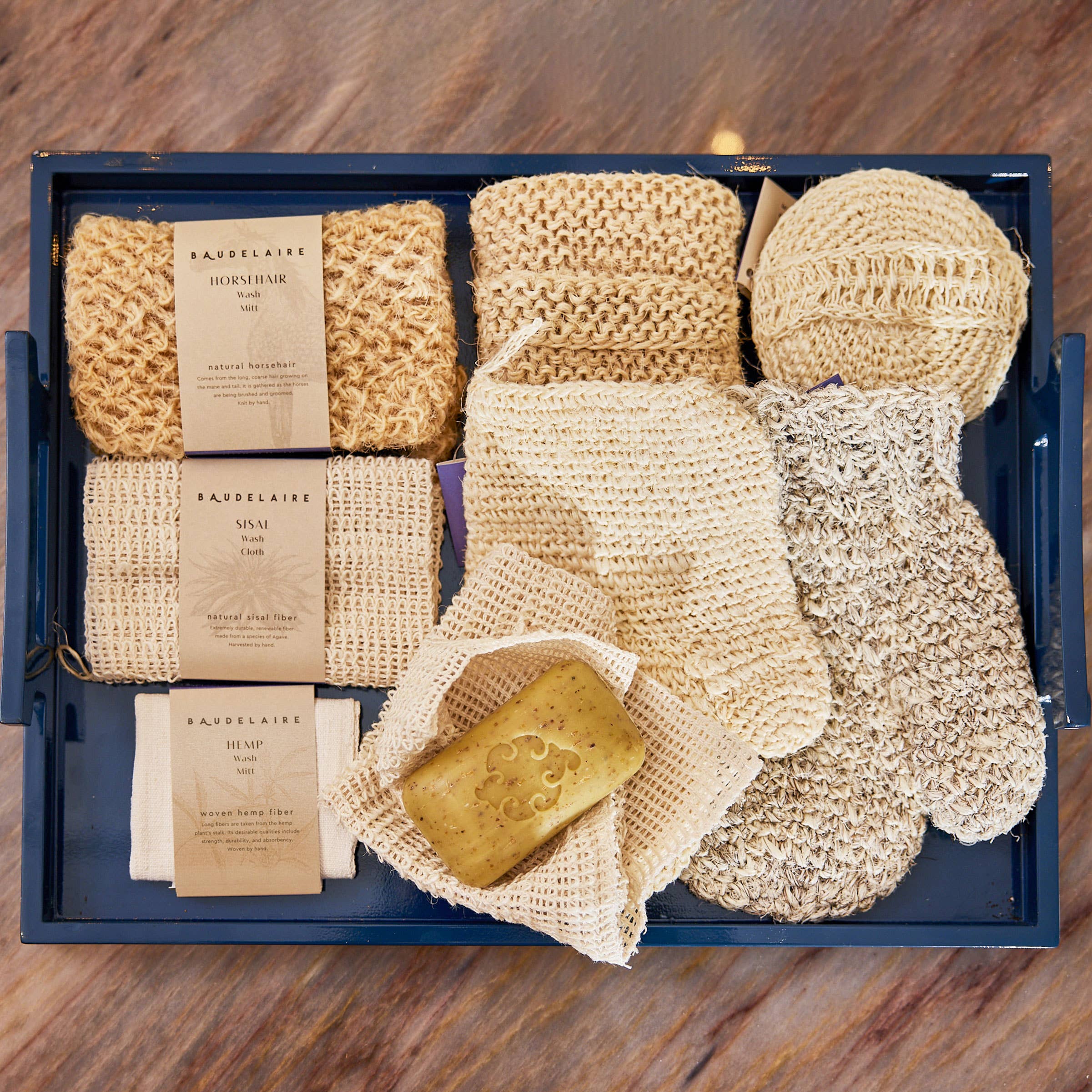 Set of natural cleaning products including sponges, cloths, and soap on a wooden surface.
