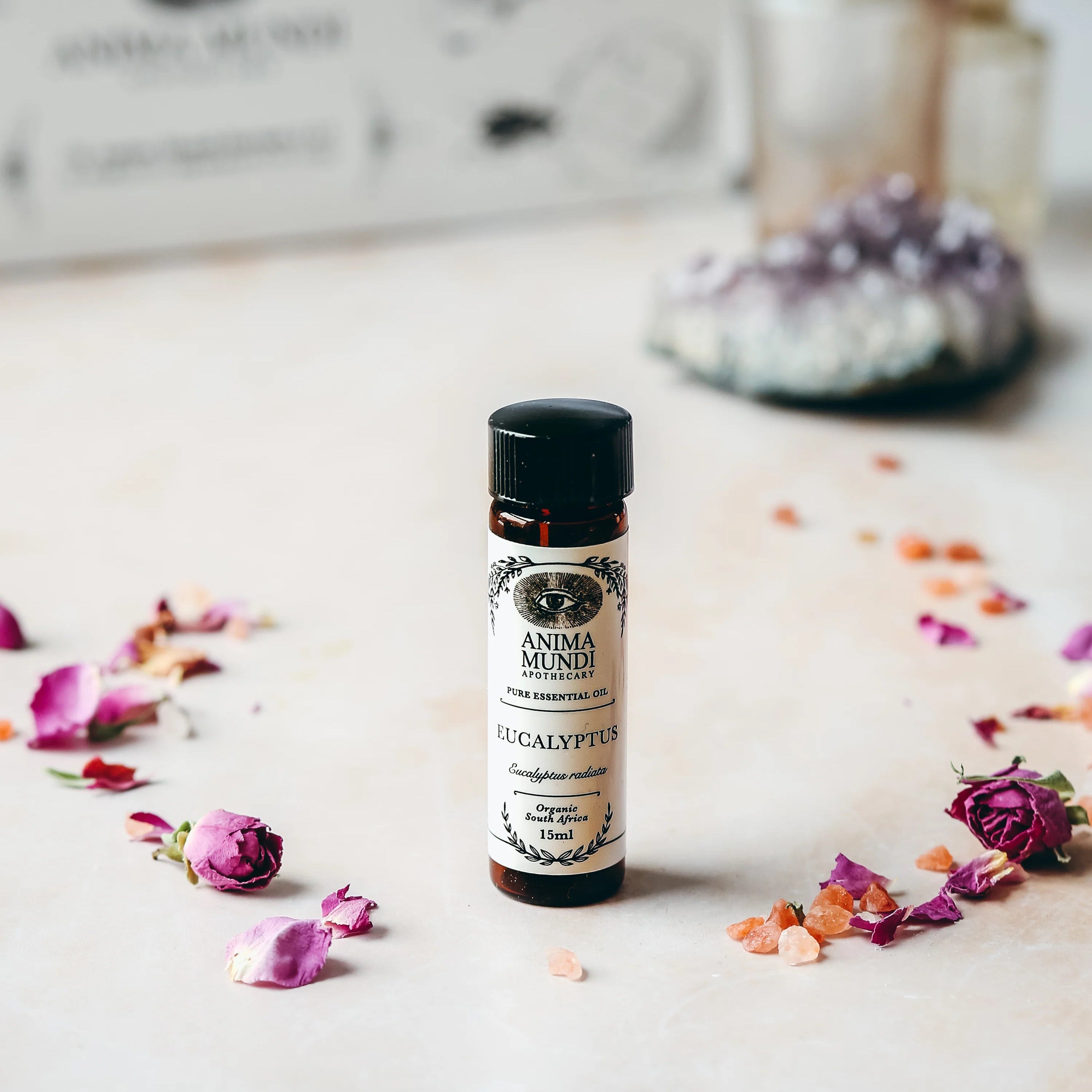 Vial labeled 'Eucalyptus' on a surface with flowers and a blurred background