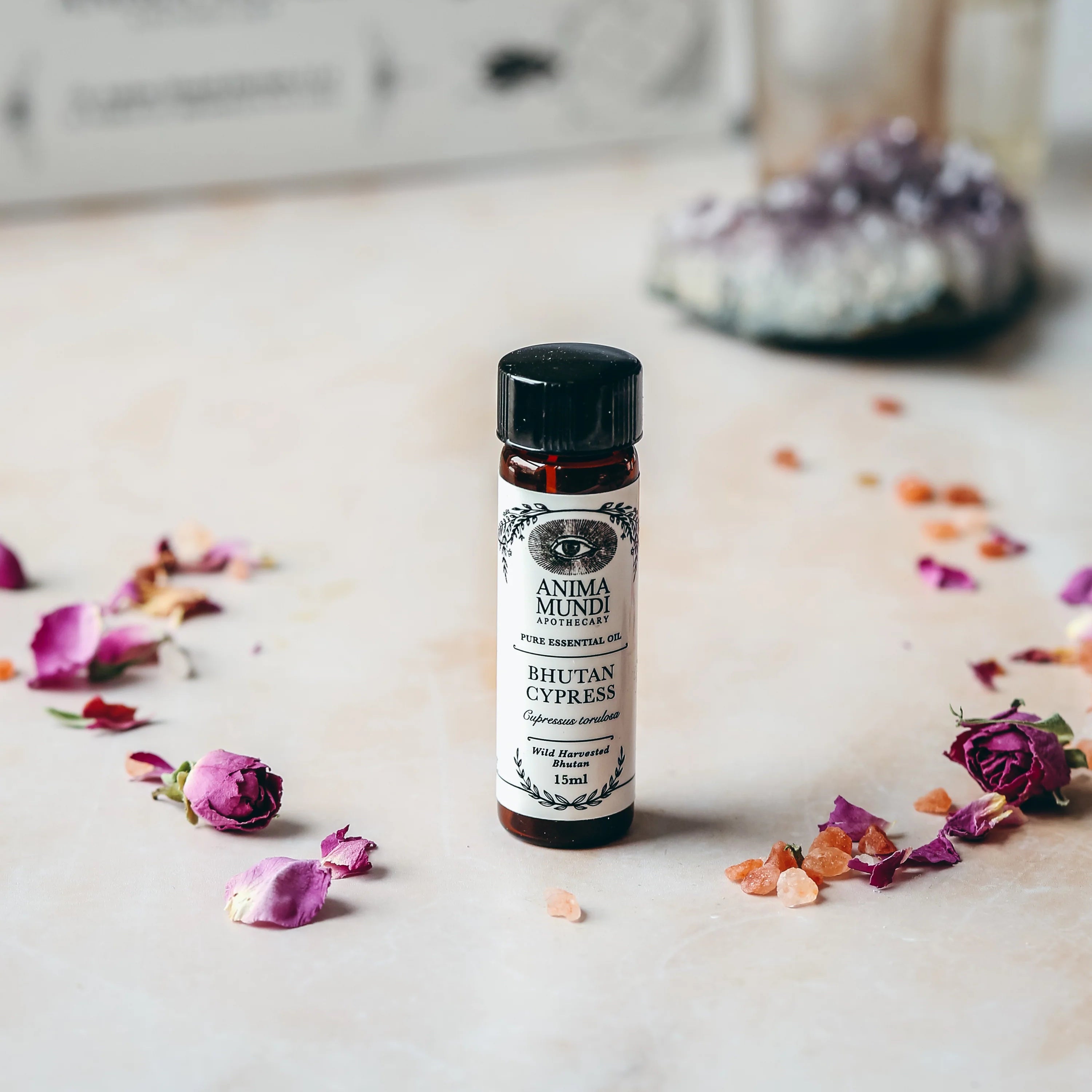 Small bottle of 'Bitteran Cypress' on a surface with flowers and a blurred background