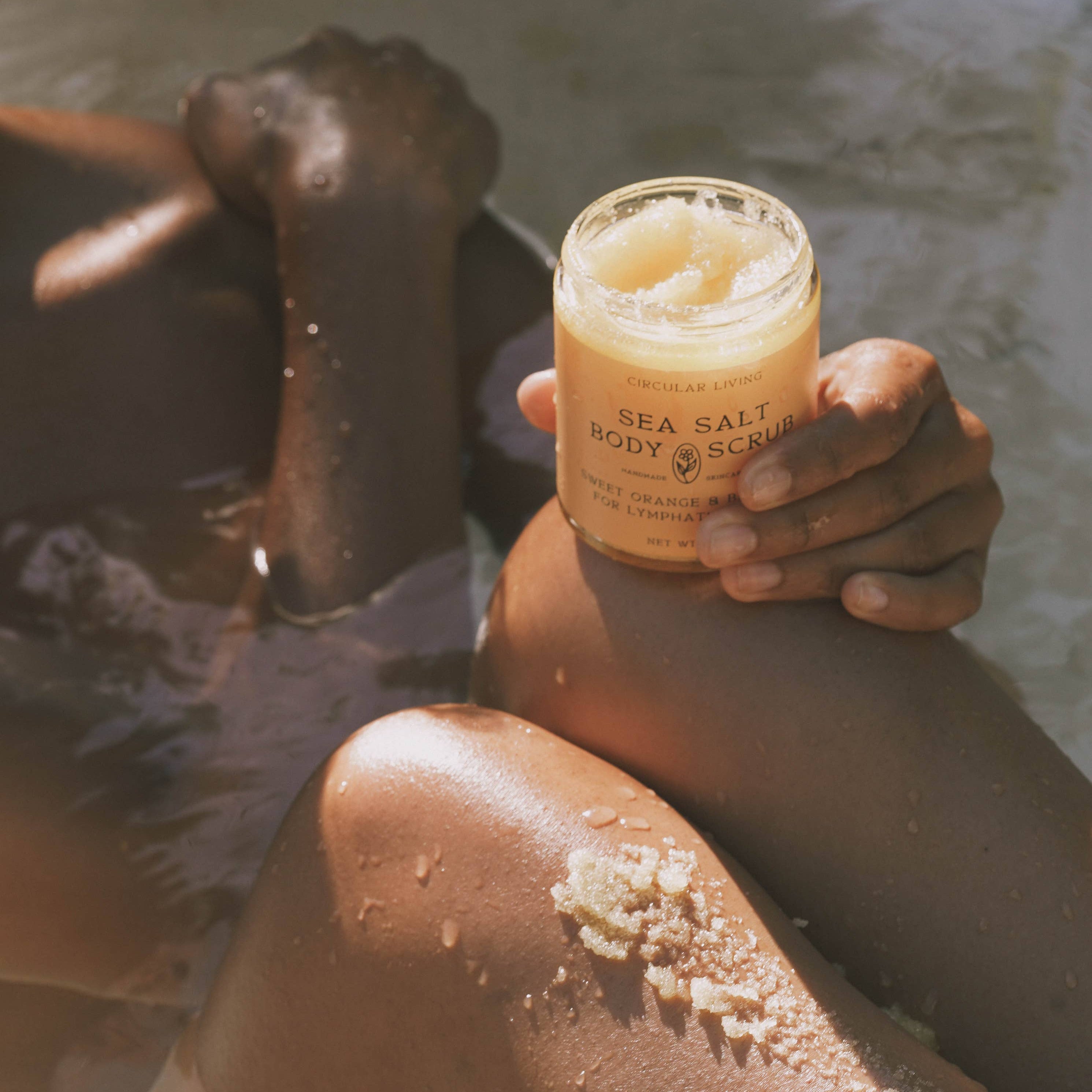 Person holding a jar of sea salt scrub with a blurred background