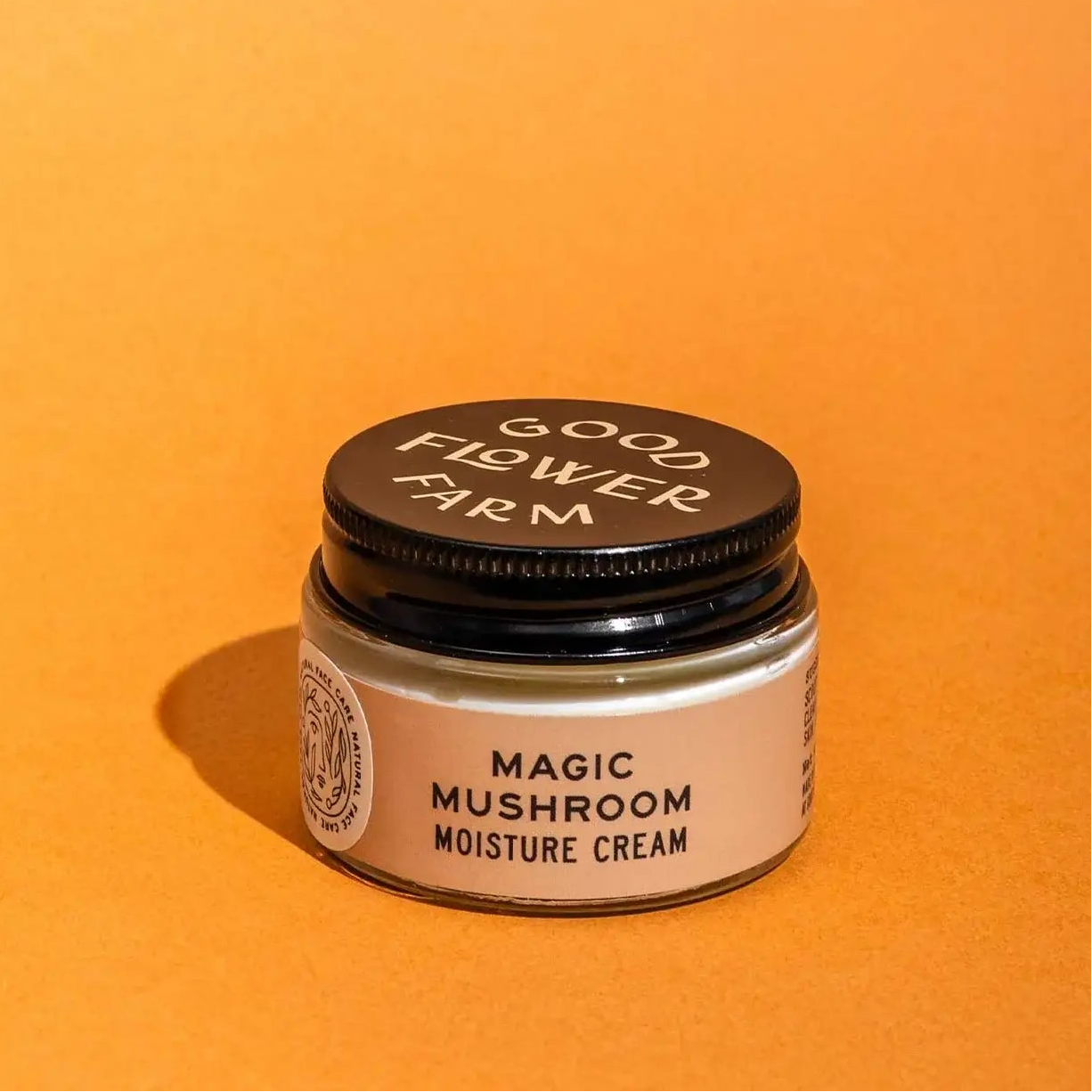 Jar of 'Magic Mushroom Moisture Cream' from 'Good Flower Farm' on an orange background