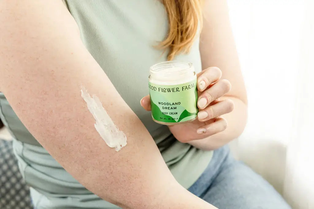 Person holding a jar of 'Woodland Farm' cream with a visible patch on their arm.