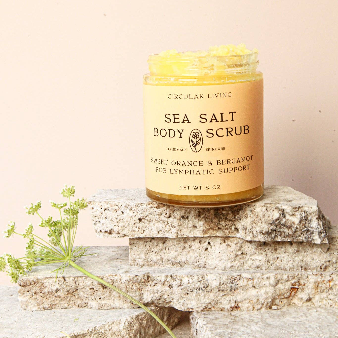 Jar of sea salt body scrub on a stone surface with a light background