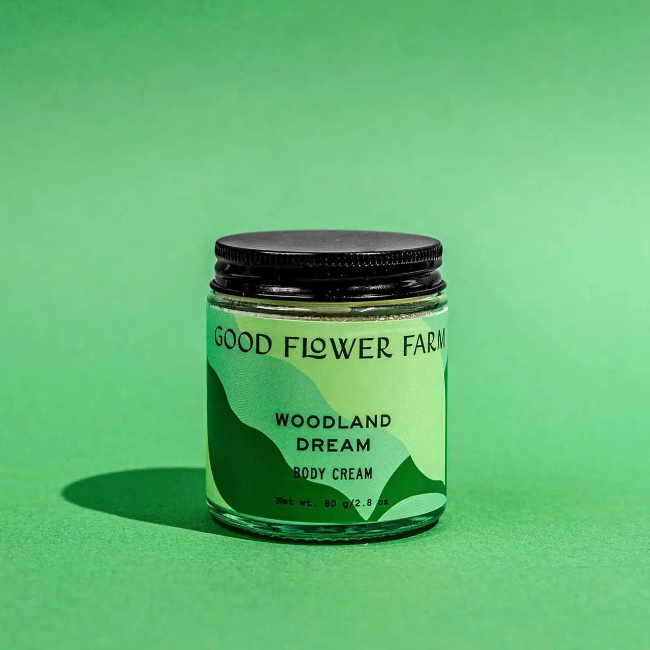 Jar of 'Woodland Dream' body cream from Good Flower Farm on a green background