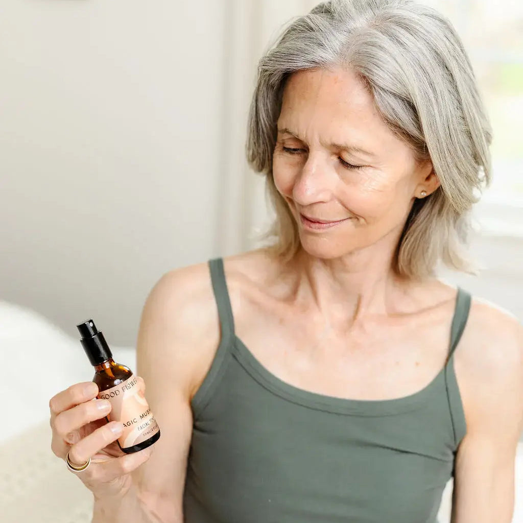 Woman holding a bottle of magic mushroom toner in a home setting