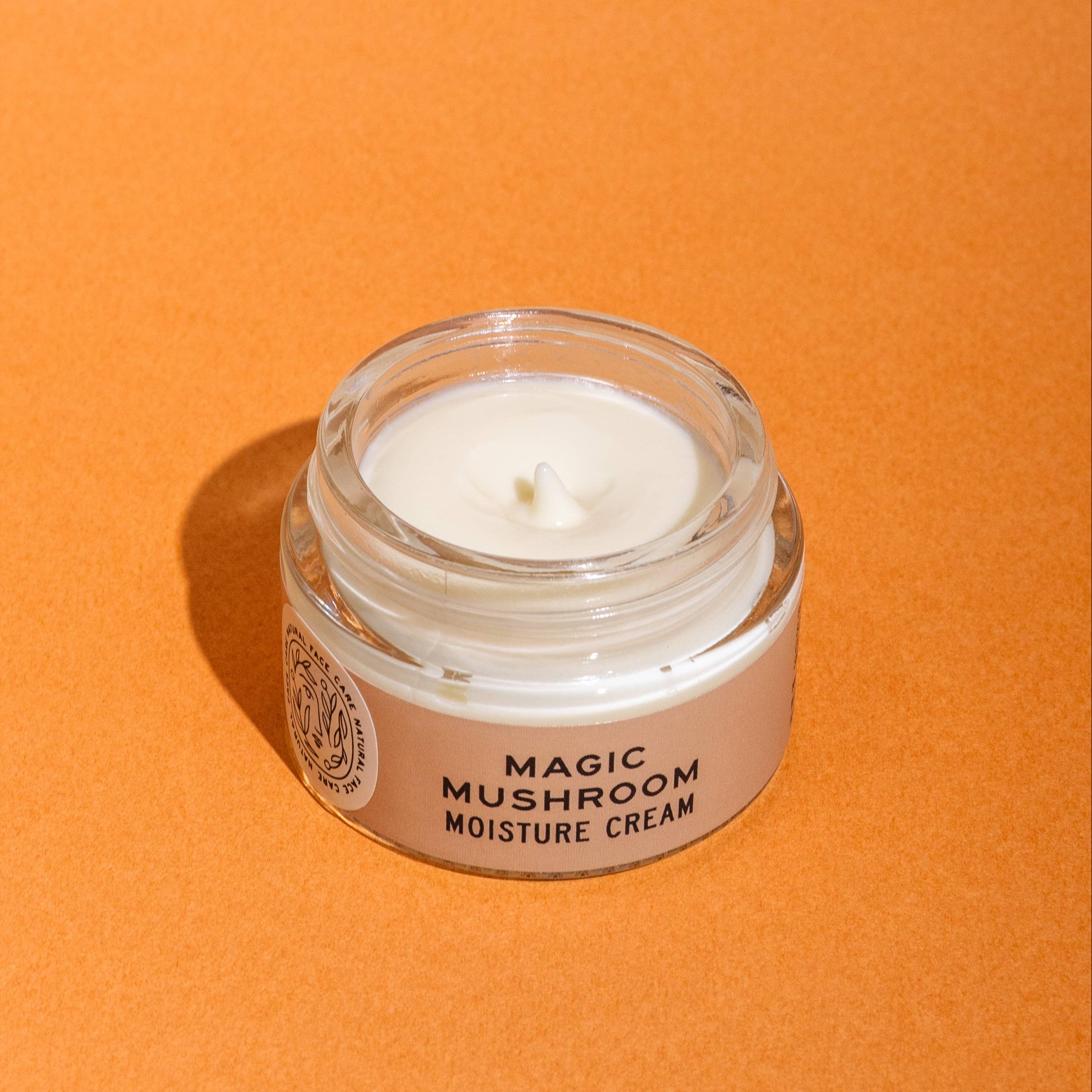 Jar of 'Magic Mushroom Moisture Cream' on an orange background