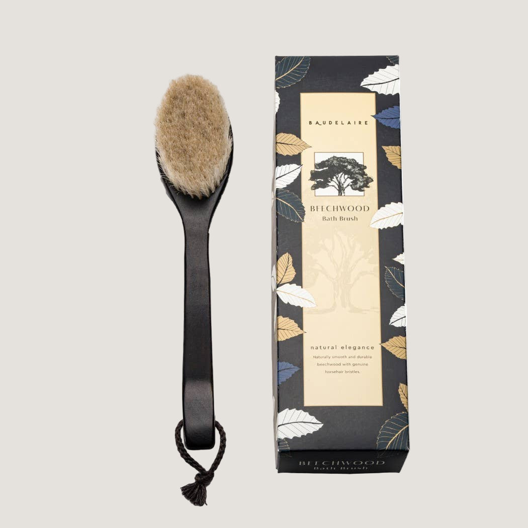 Bath brush with black handle and natural bristles next to its packaging on a white background
