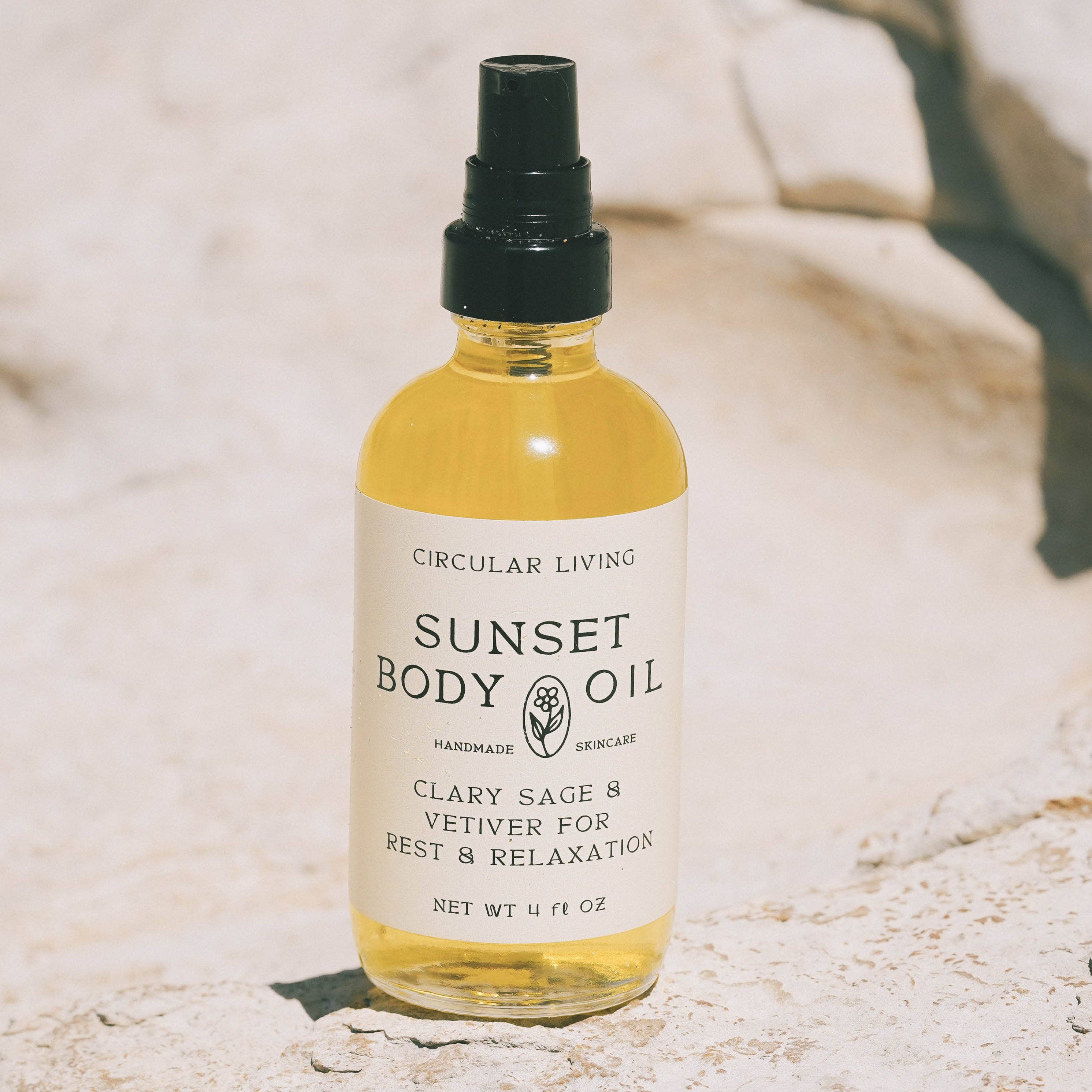 Bottle of Sunset Body Oil on a textured surface